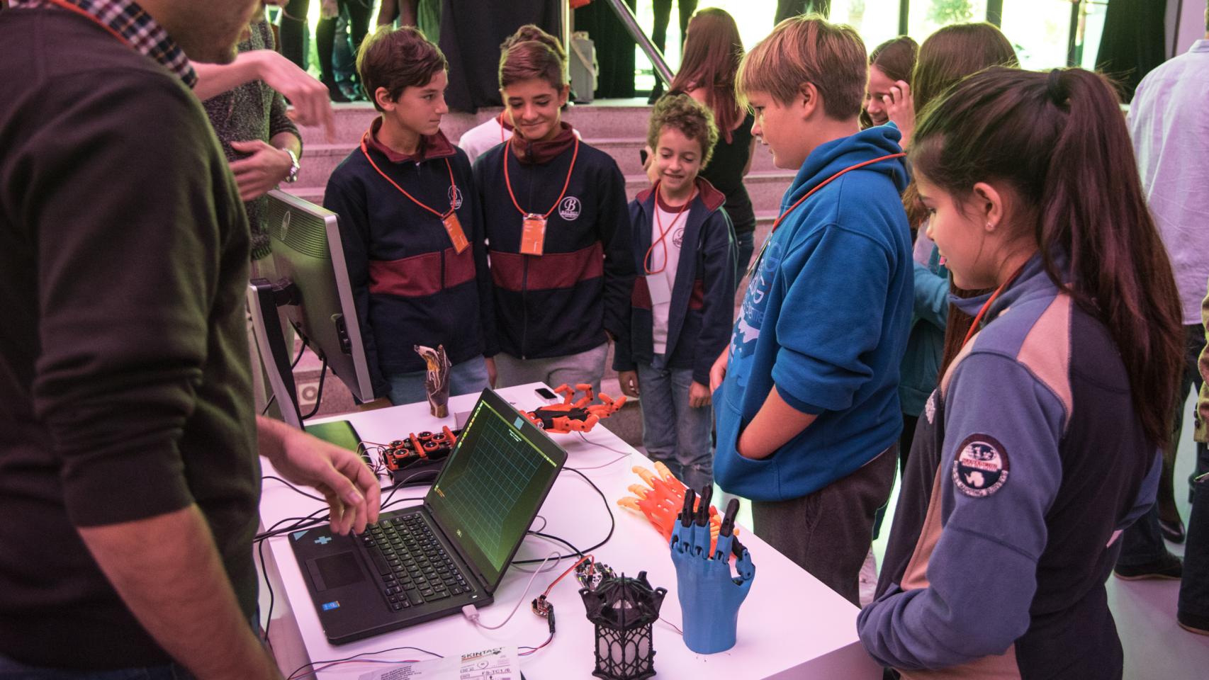 Unos niños observan una mano biónica.