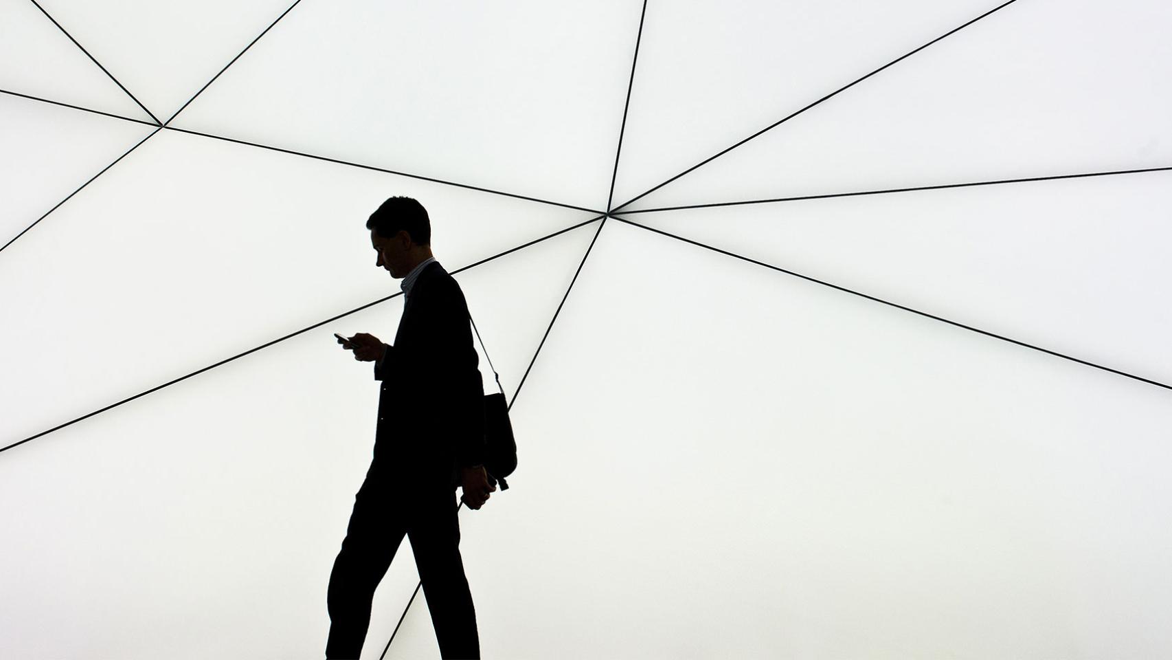 Un hombre camina mientras consulta el móvil.