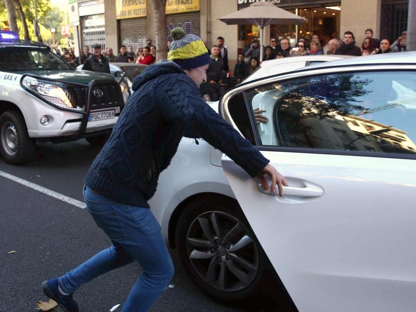 Un familiar de uno de los detenidos intenta sacar al arrestado del coche de los agentes de la Guardia Civil,