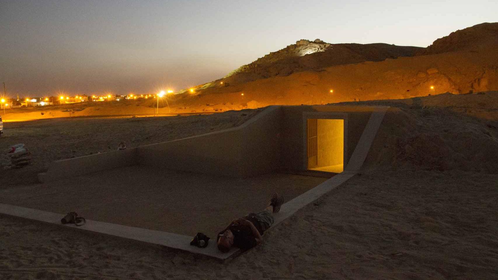 Un trabajador descansa, en el exterior de la réplica de la tumba.