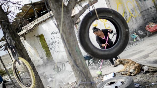 Una vecina barre en su casa.