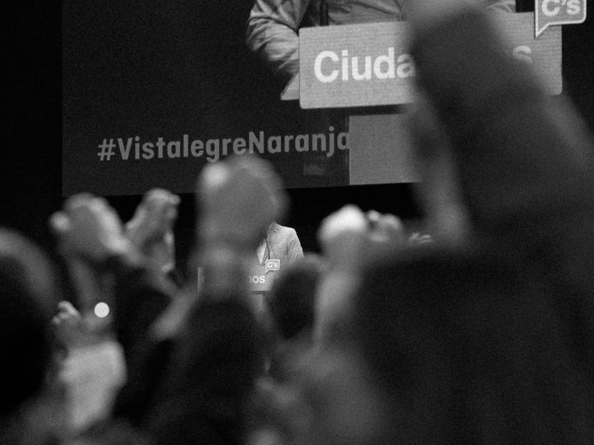 El público alza sus manos formando una cadena mientras Rivera habla.