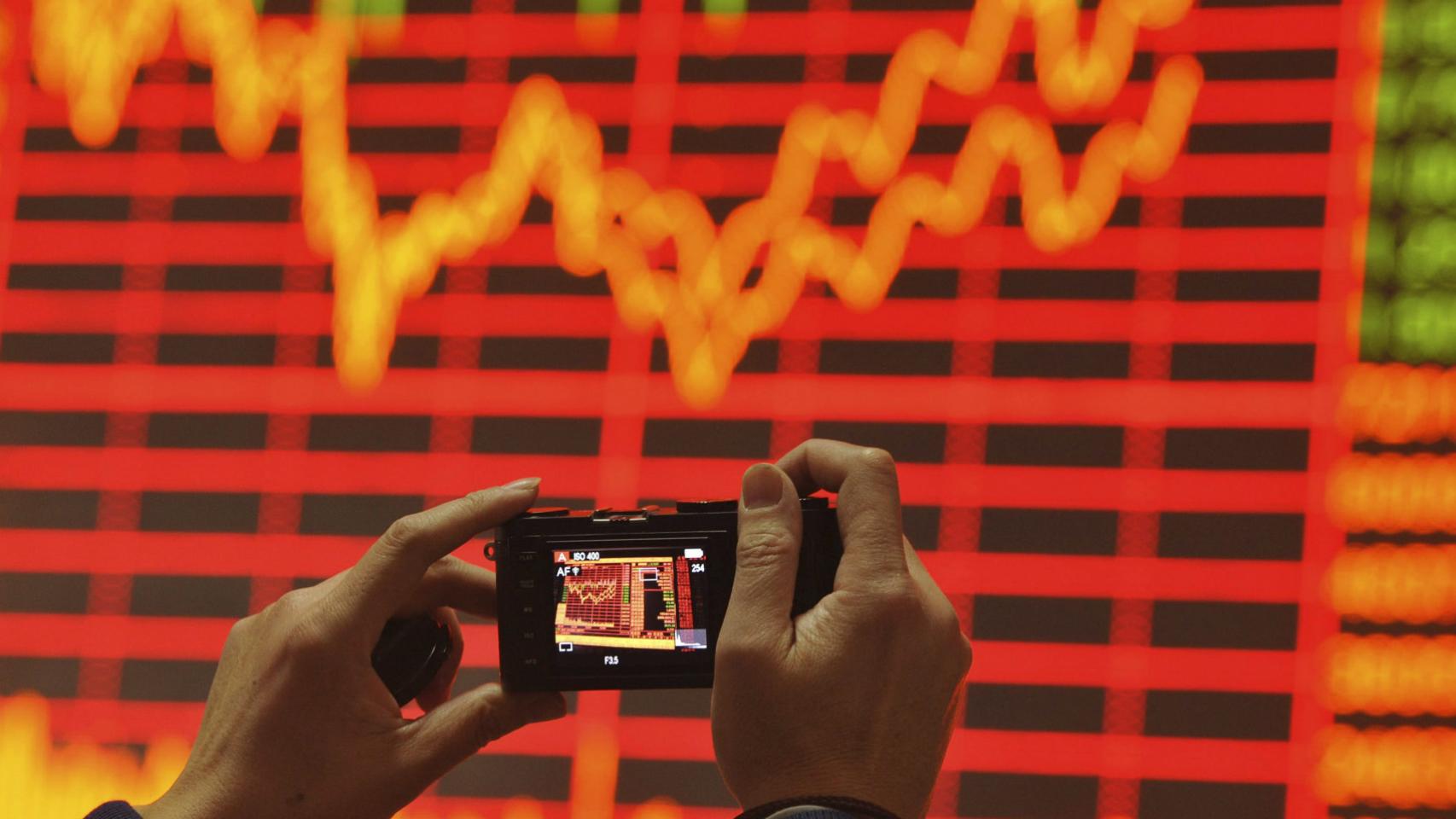 Un inversor fotografía una panel de cotizaciones.