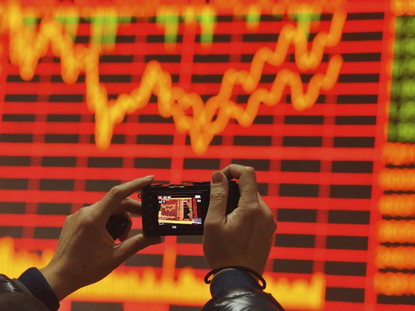 Un inversor fotografía una panel de cotizaciones.