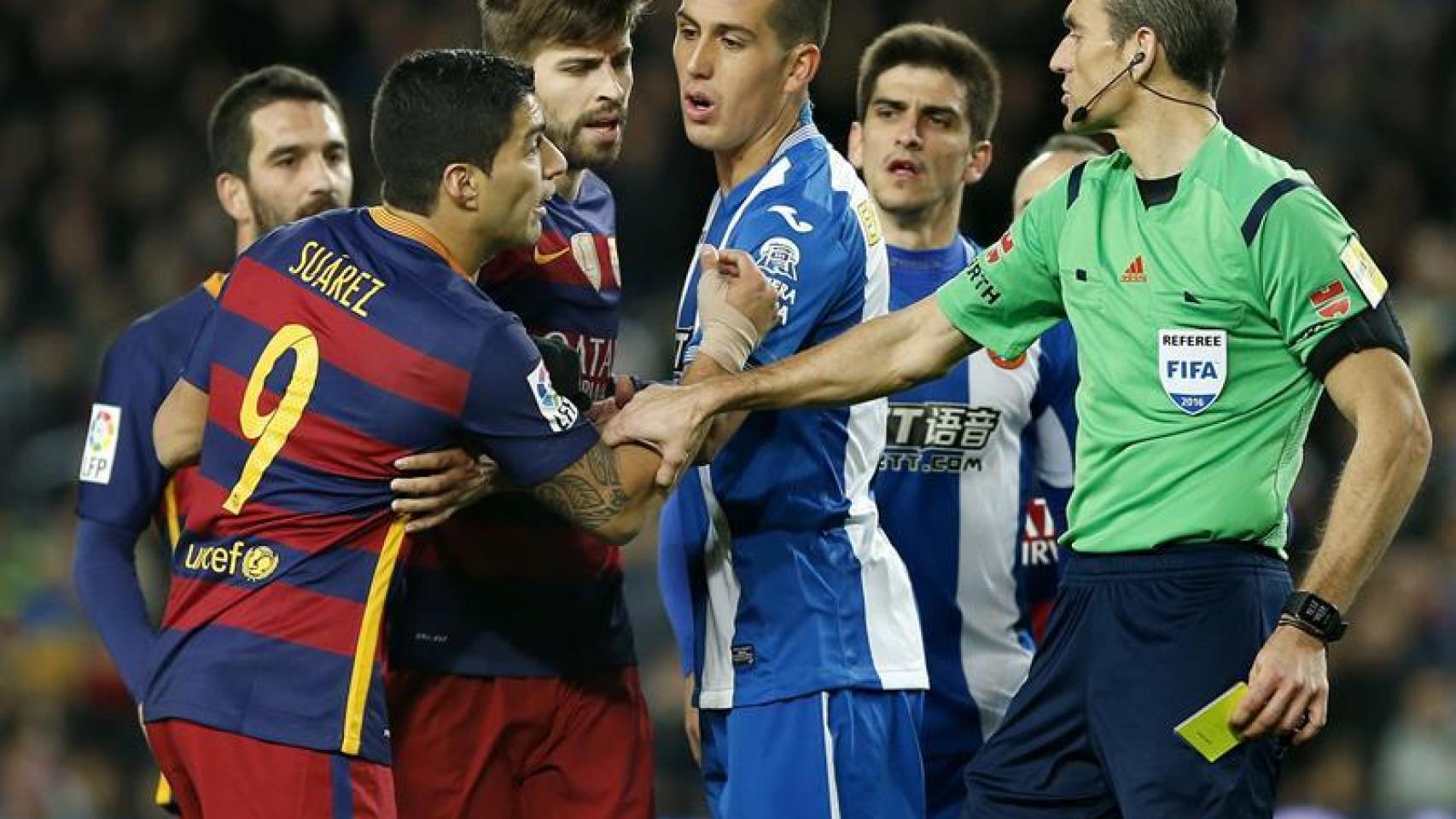 El árbitro Martínez Munuera saca una amarilla a Piqué durante el encuentro.