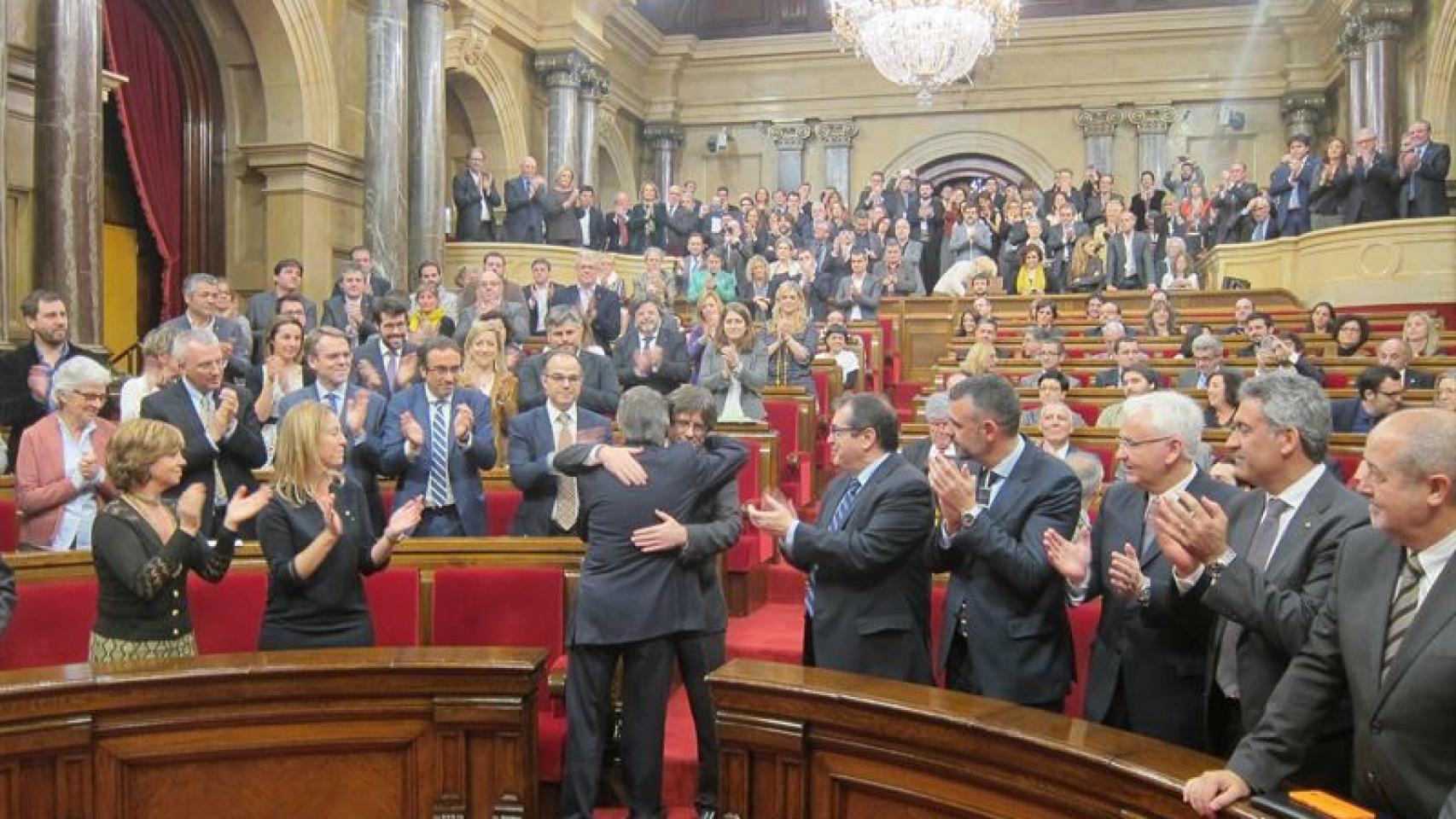 El Parlament aplaude el abrazo entre Artur Mas y Carles Puigdemont.