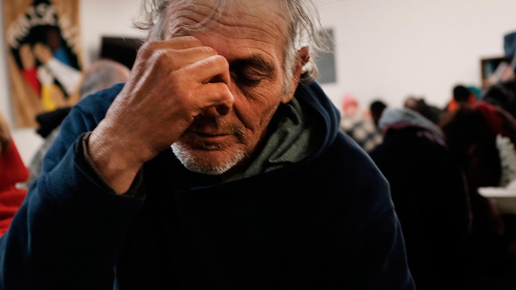 Una persona sin hogar reza mientras espera asistencia.