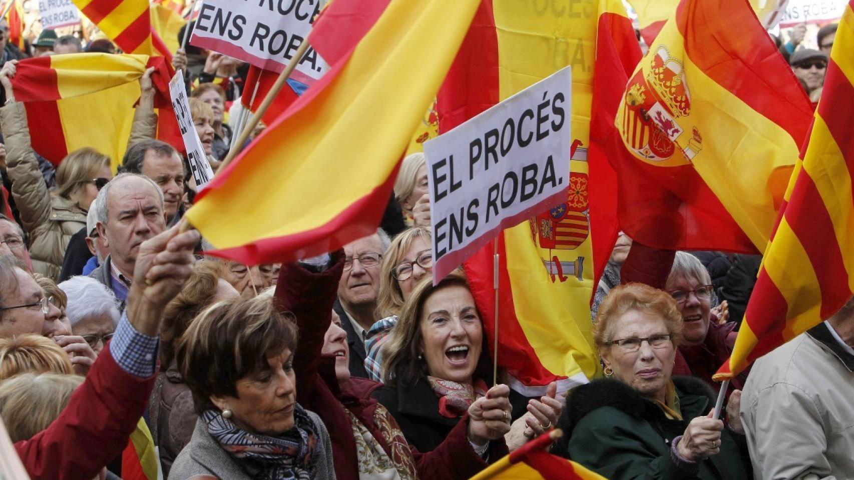 Manifestantes con pancartas en las que se lee 'El procés ens roba'.