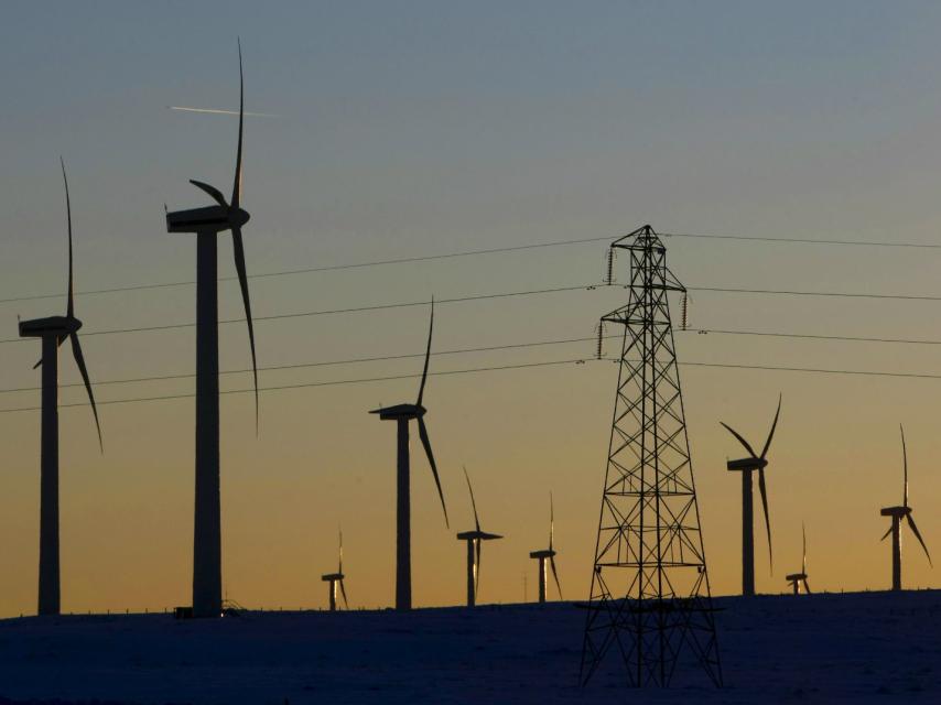 Turbinas eólicas junto a una torre de tensión.