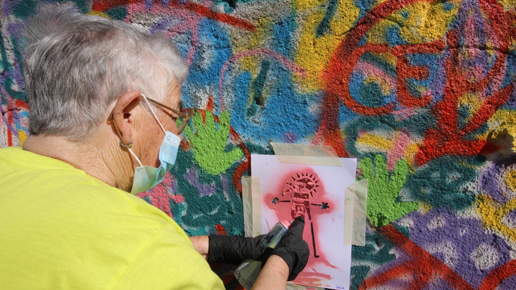 Una de las ancianas dibujando con plantilla y spray