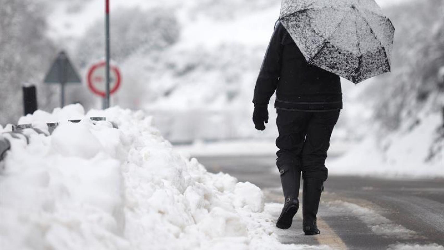Una mujer camina entre la nieve por una carretera de Lugo