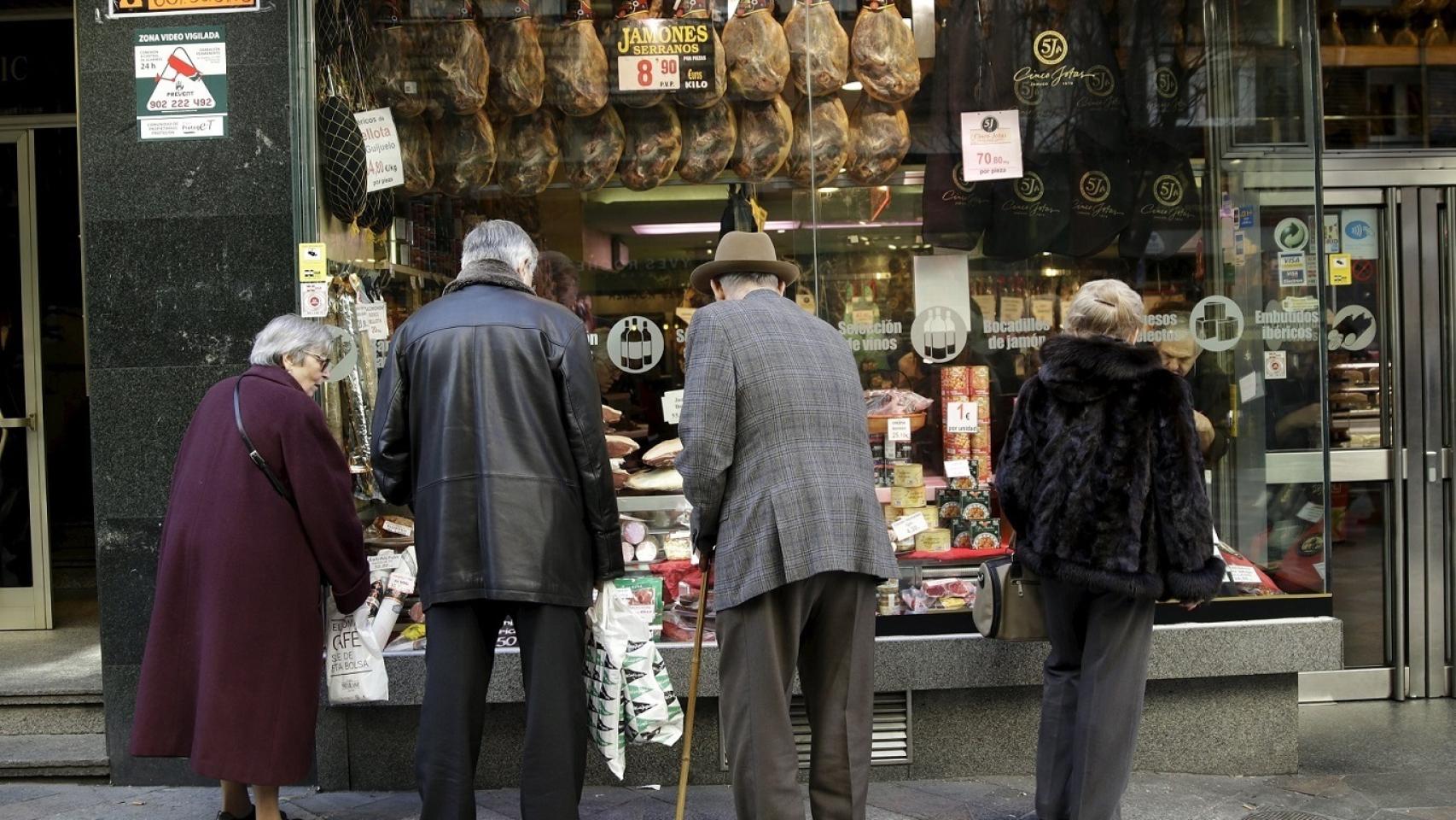 Un grupo de jubilados ante un escaparate de embutidos en Madrid