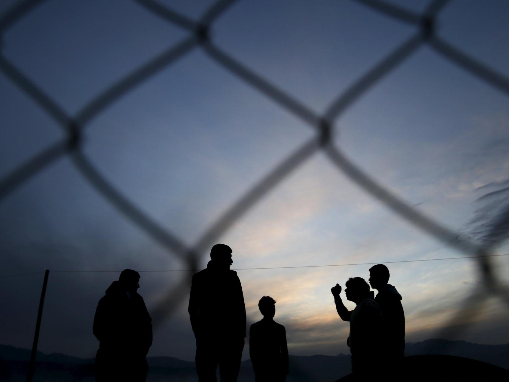 Un grupo de migrantes esperan para cruzar la frontera entre Grecia y Macedonia