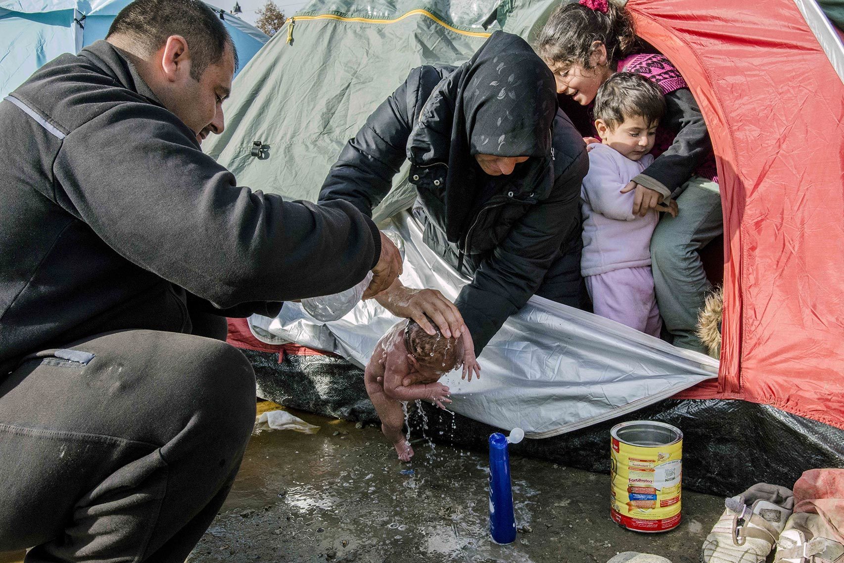 Los padres de Bayan la bañan en el campo de Idomeni.