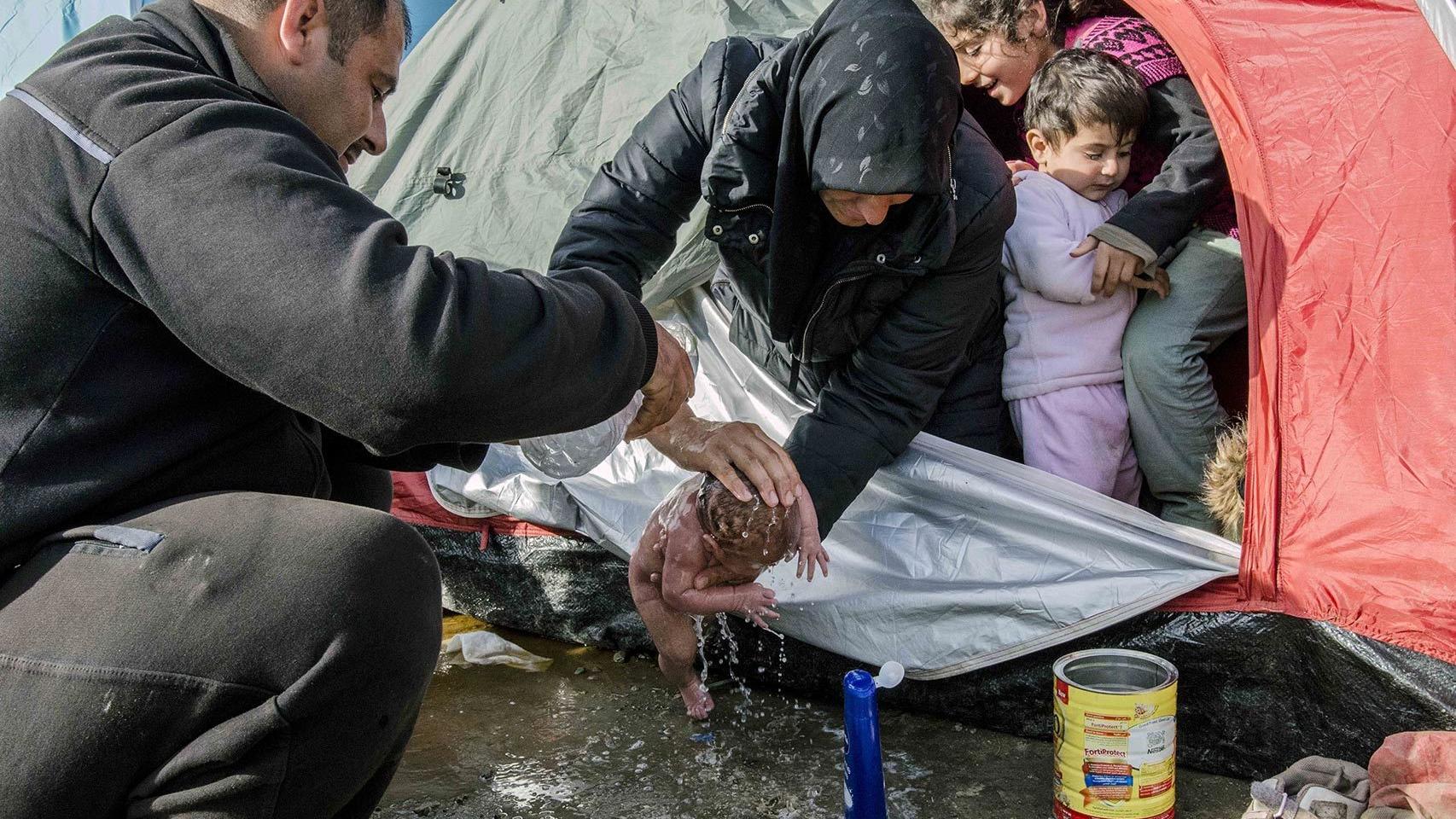 Los padres de Bayan la bañan frente a su tienda de campaña en Idomeni.