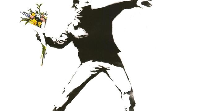 Un activista lanza un ramo de flores en una de las obras más populares de Banksy