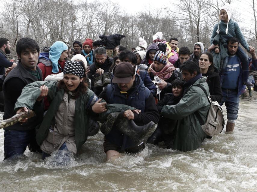 Refugiados en un campamento cerca de Idomeni cruzan un río en la frontera con Macedonia