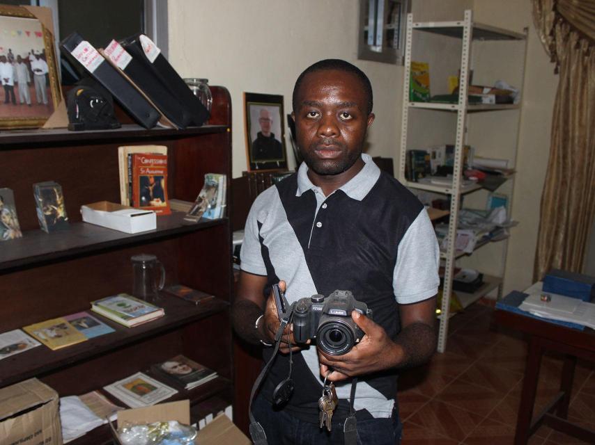 El padre Nestor Banboye muestra la cámara de Manuel.