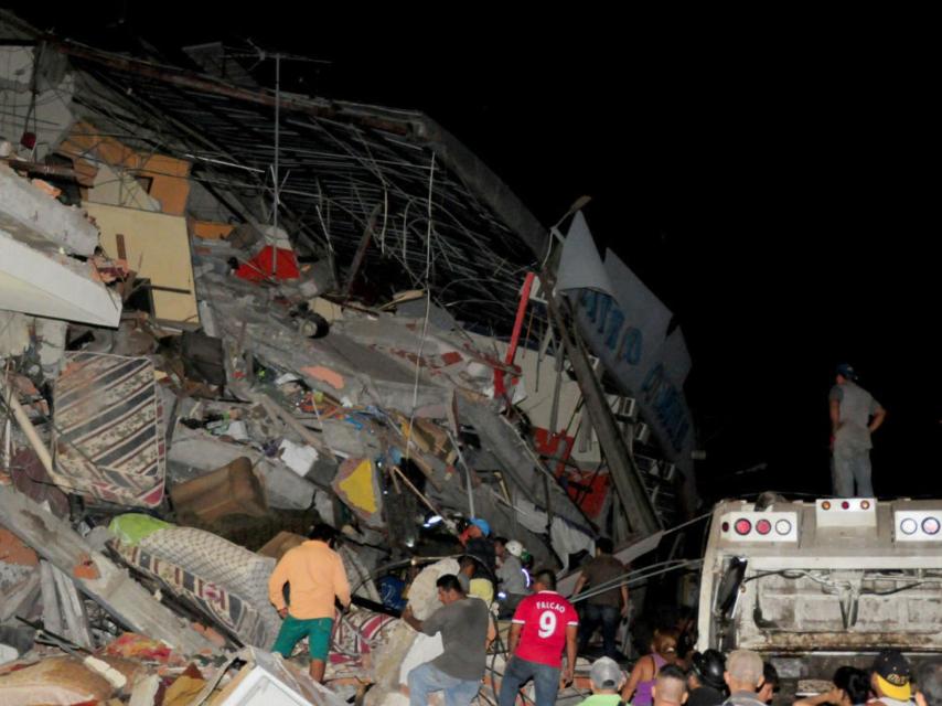 Varias personas buscan entre las ruinas de un edificio en la zona de Manta.