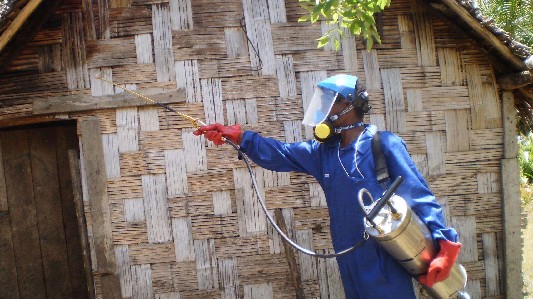 Un trabajador fumiga una cabaña para prevenir la malaria en Vanuatu.