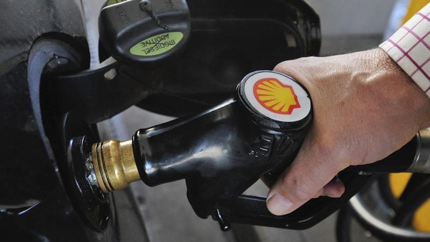 Un hombre reposta su coche.