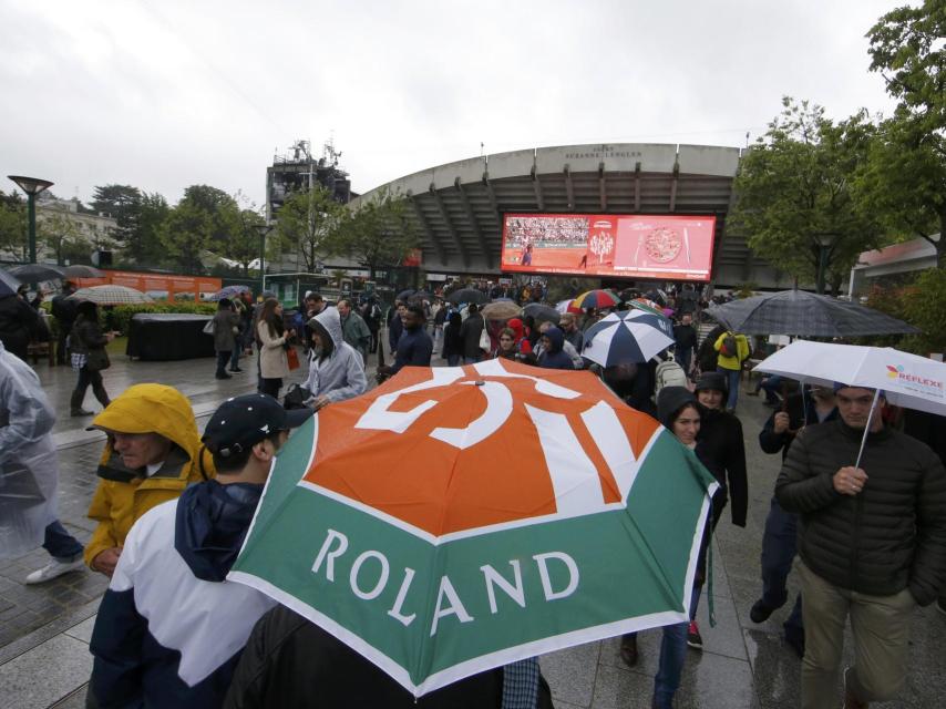 Los aficionados pasan por Roland Garros con paraguas.