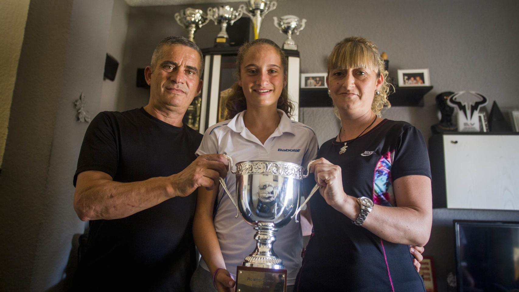 María Dolores, entre sus padres, sosteniendo el trofeo ganado en París.