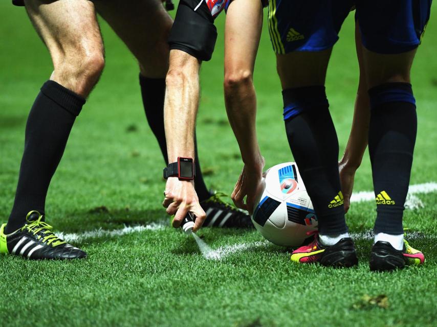 Un árbitro marca la línea para tirar una falta.