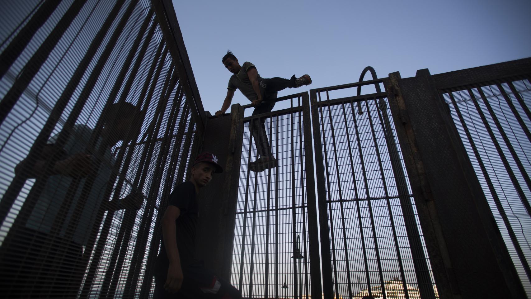 En el centro, Mohamed, junto a dos menores que saltan la valla del puerto melillense.
