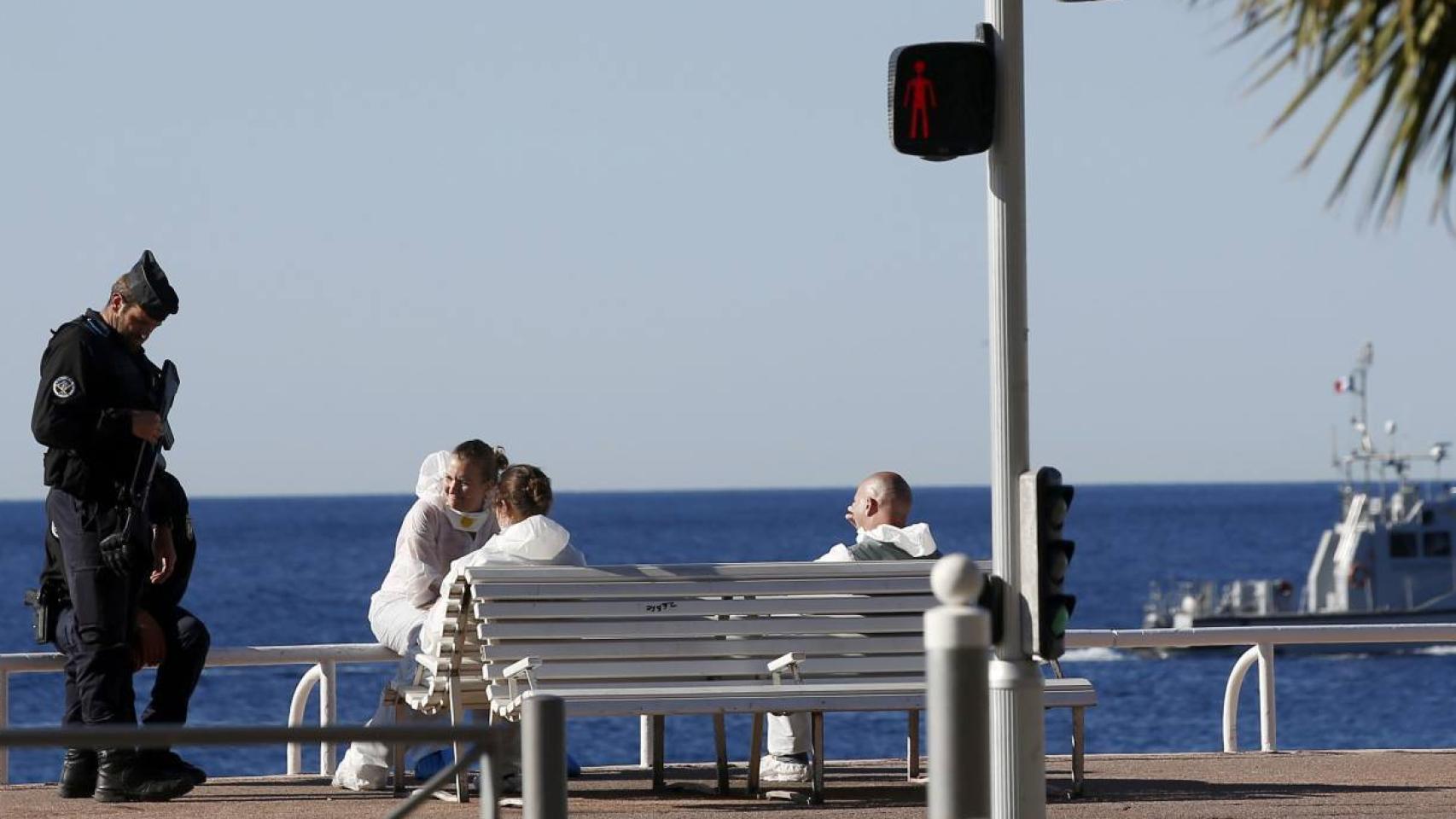 Policías que toman pruebas en la escena del atentado descansan al amanecer.