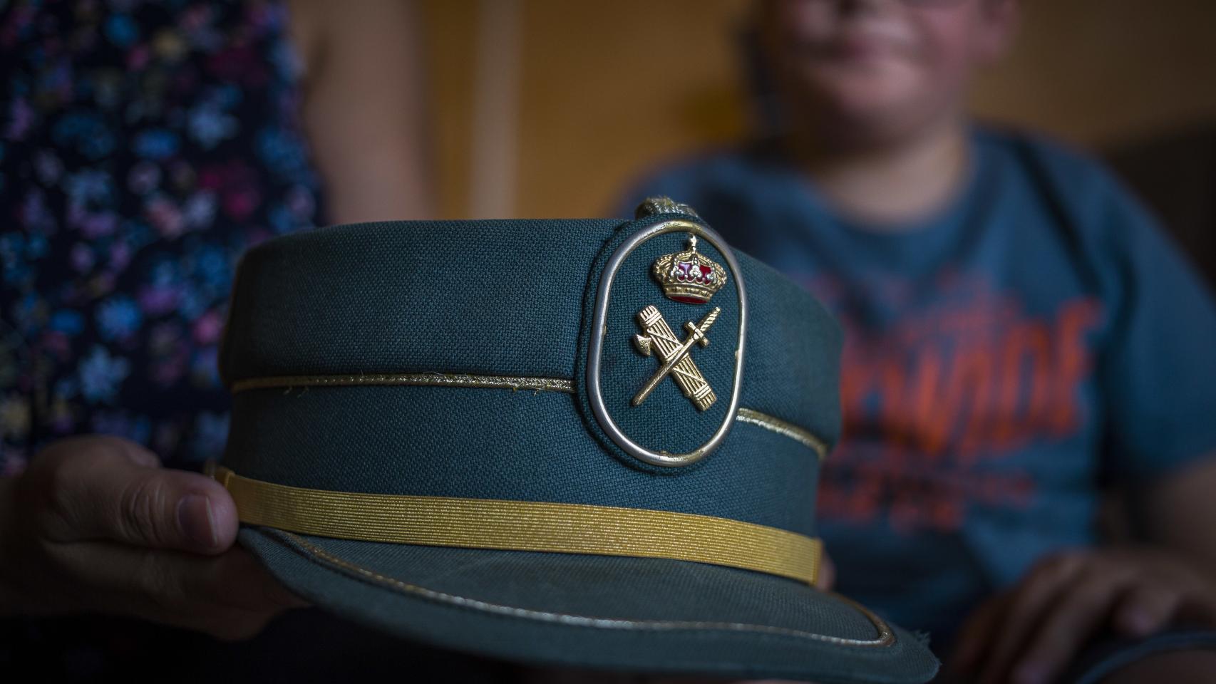 La gorra del guardia civil José Manuel Herrera sostenida por su mujer. Detrás, su hijo con autismo.
