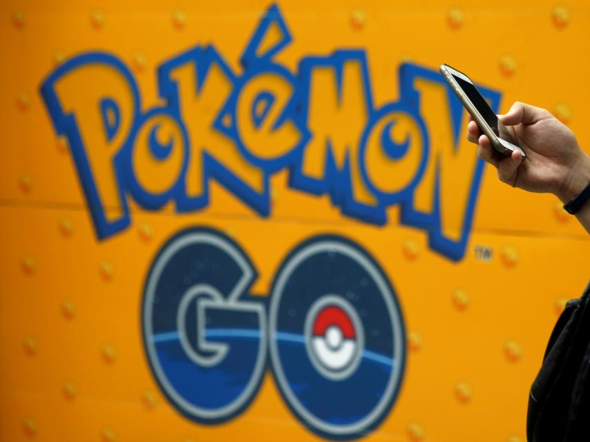 Un hombre usa su móvil frente a un cartel de Pokémon Go en Tokyo.