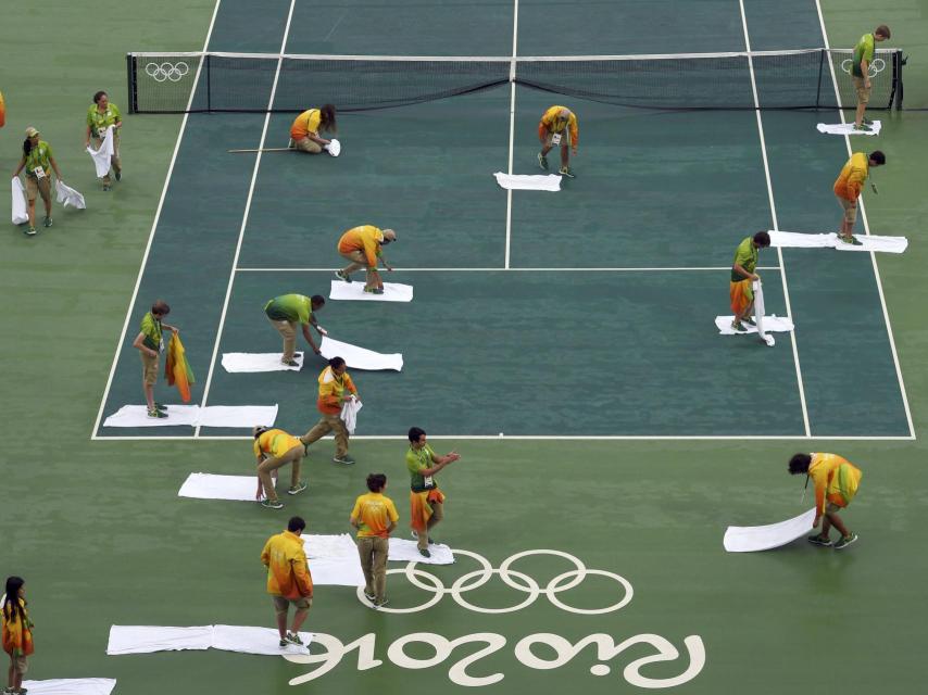 Los voluntarios brasileños limpian la pista de tenis.