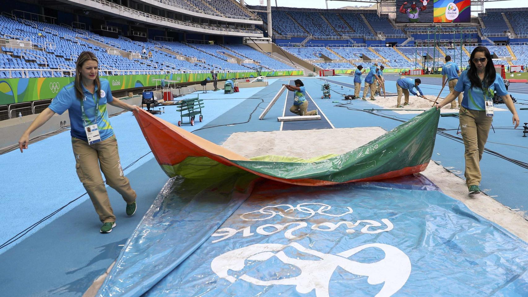 Unos voluntarios realizan los últimos preparativos en una pista de atletismo