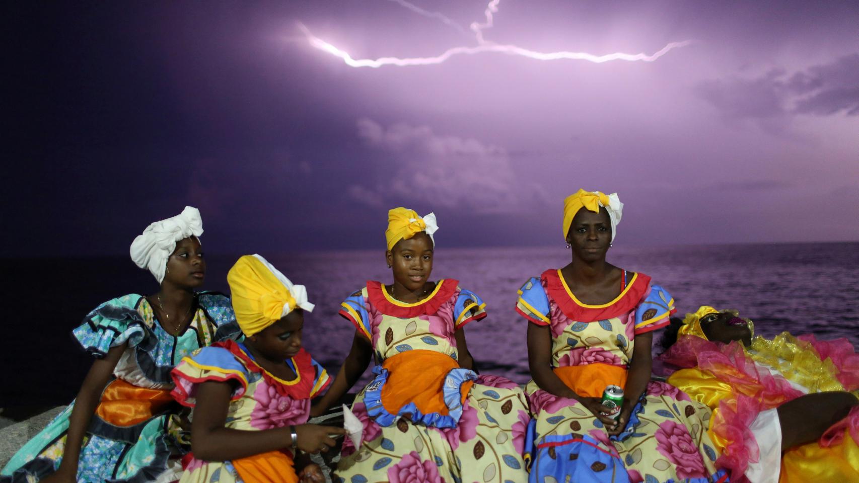 Varias mujeres conversan en el Malecón habanero antes de bailar en el desfile en honor a Castro.