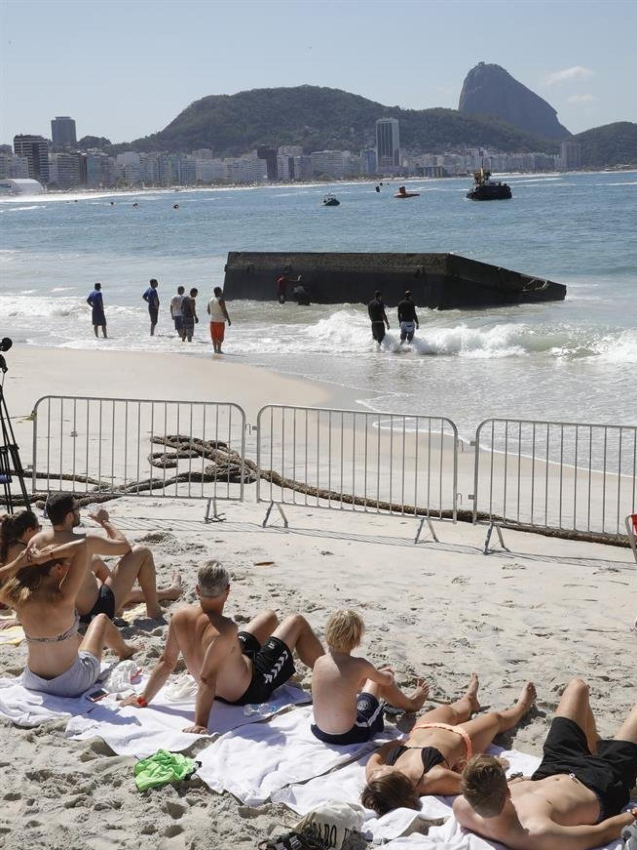 Los bañistas observan los trabajos de los operarios.