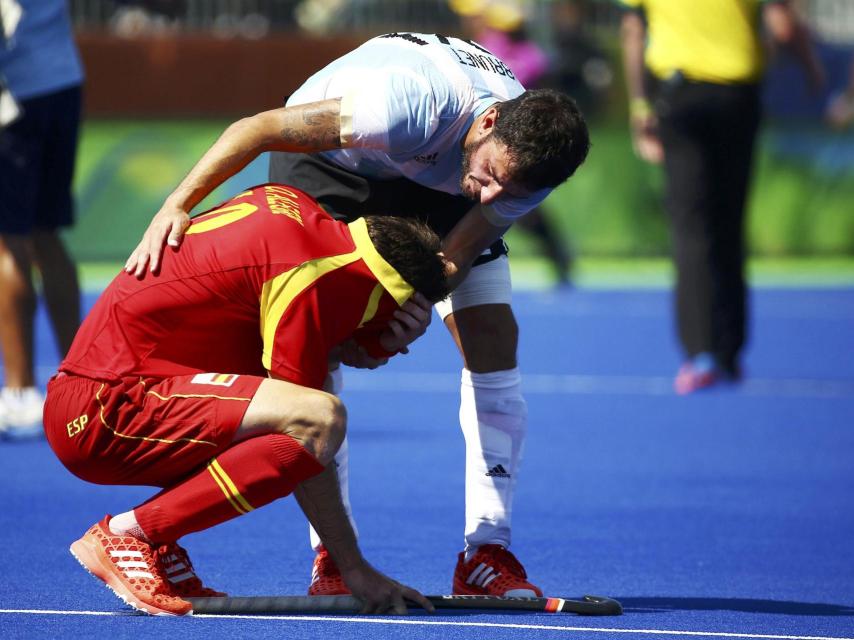 Un jugador argentino consuela a David Alegre tras la eliminación en el hockey.
