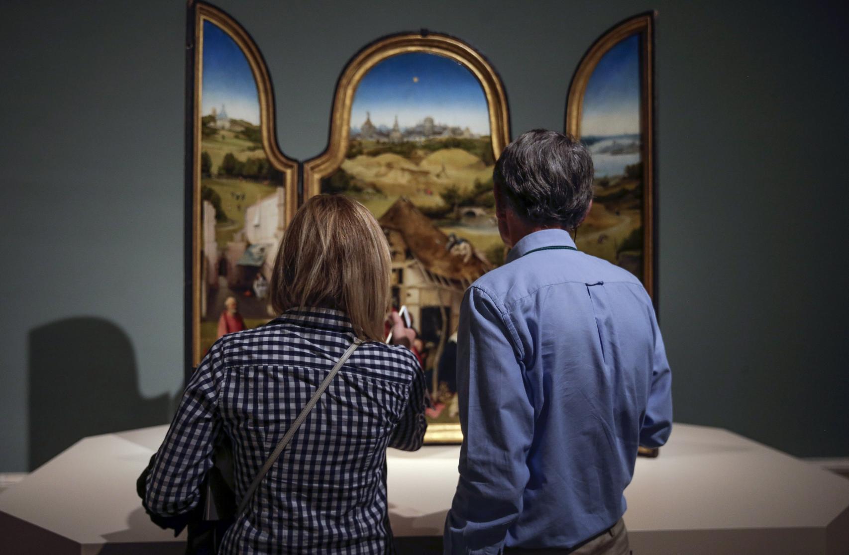 Dos visitantes ante el tríptico de La adoración de los magos.