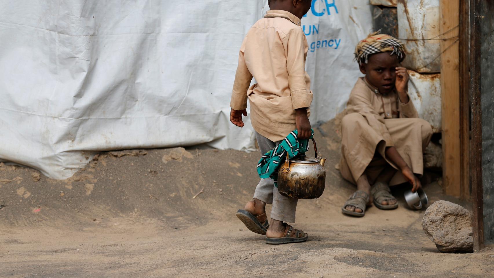 Un niño carga con una tetera en un campo de desplazados cerca de Sanáa. | Reuters
