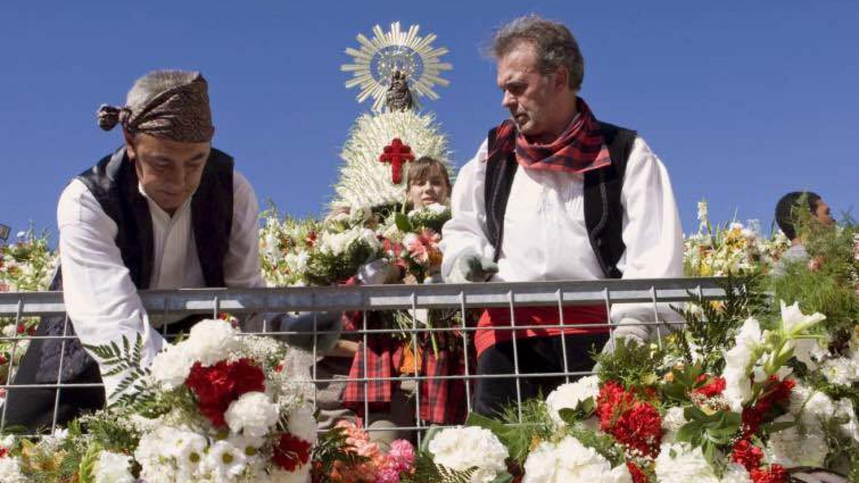 Voluntarios colocan flores en el manto de la Virgen