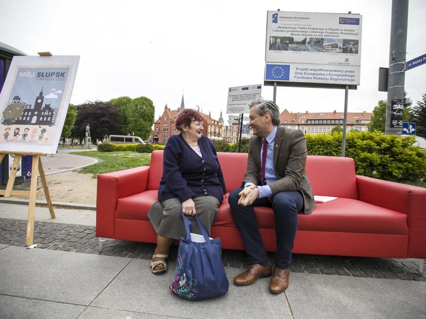 Biedron disfruta en su sofá rojo conversando con una ciudadana.