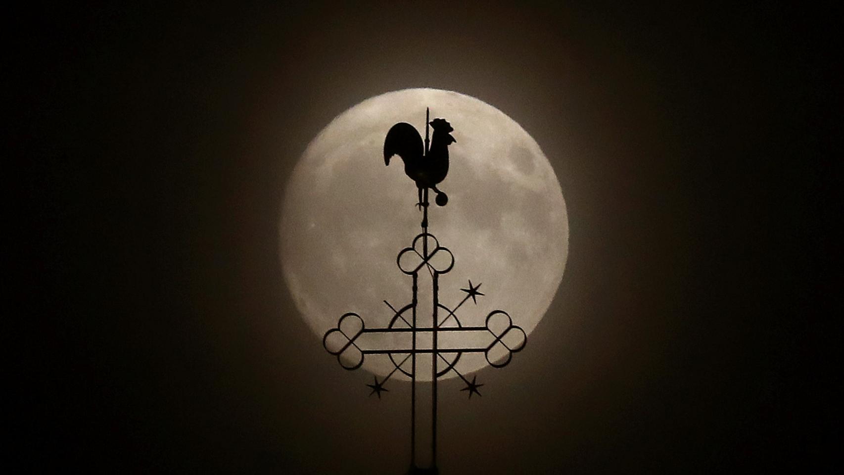 La veleta de una iglesia en Klein-Auheim, Alemania, contra la superluna.