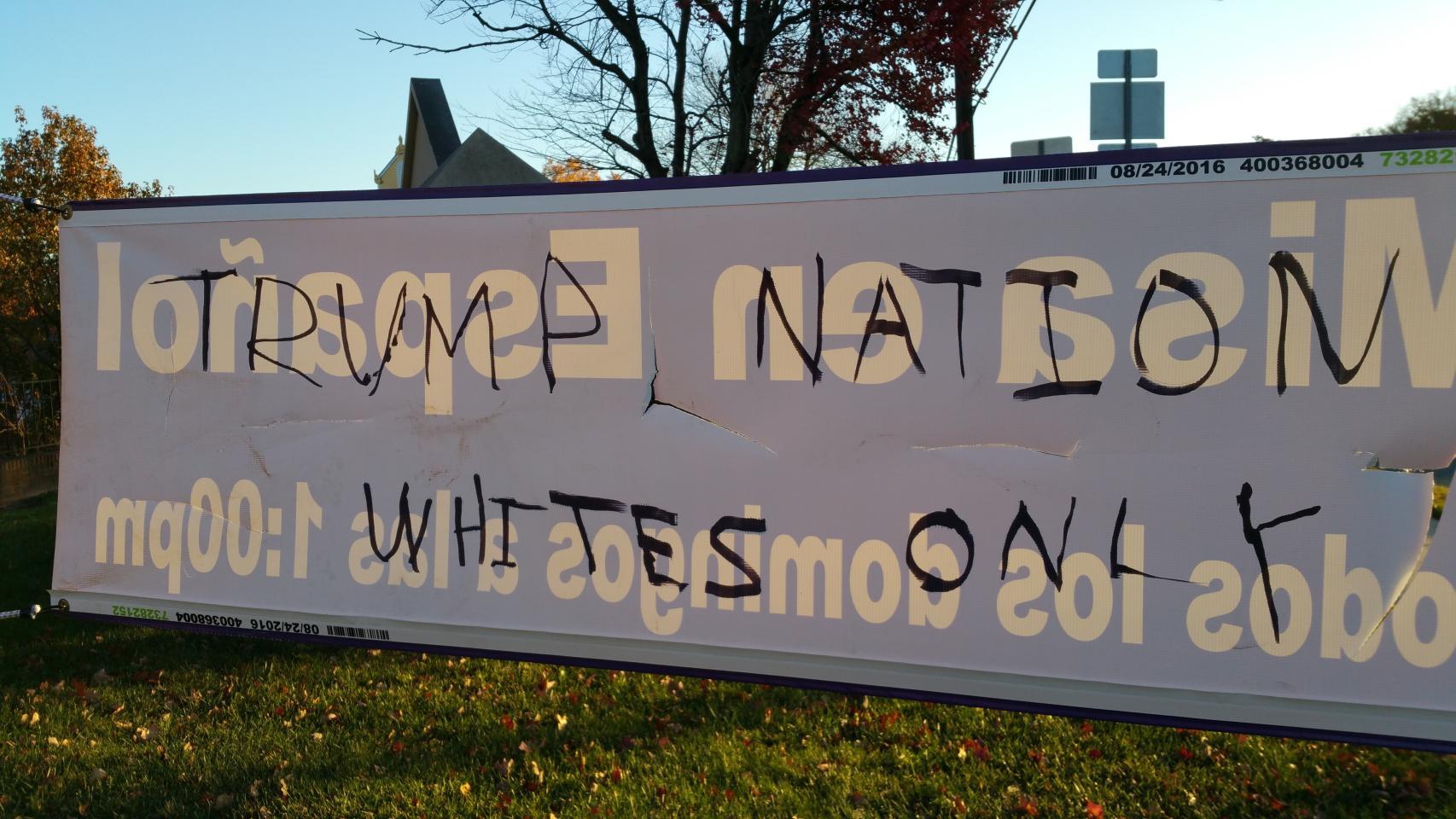 La pintada de -Nación Trump: sólo blancos- en el reverso del cartel roto que anuncia misas en español.