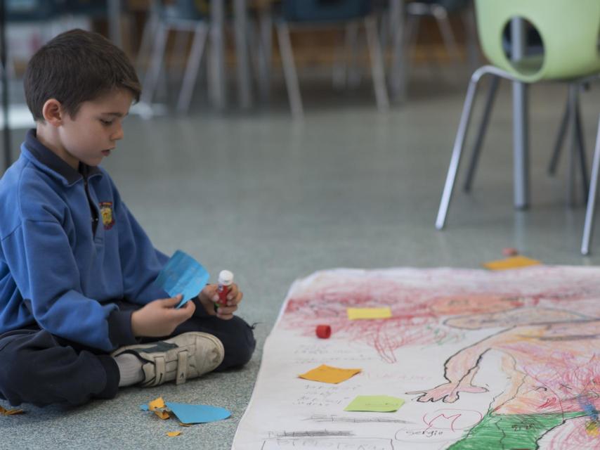 Uno de los alumnos pegando sobre el mural lo que piensa sobre sus compañeras