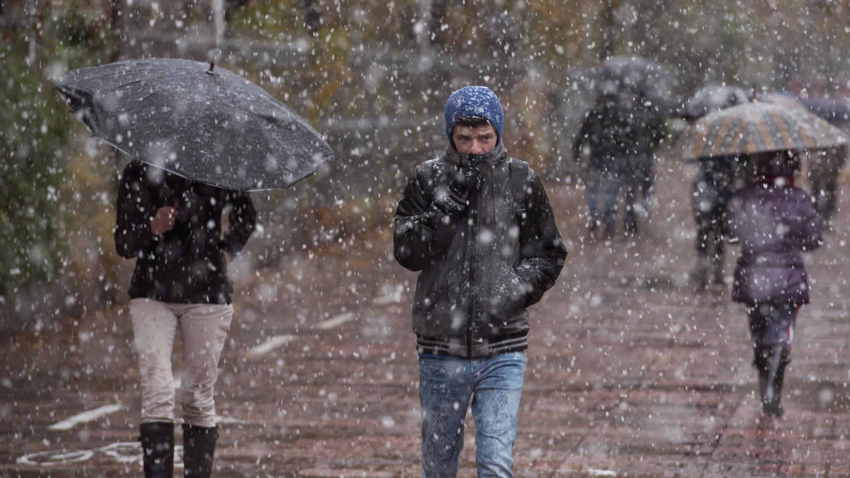 Un joven intenta protegerse de la nevada por las calles de Vitoria.