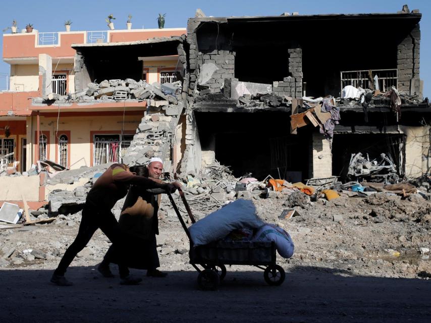 Dos hombres pasan ante un edificio destruido por los enfrentamientos en Mosul.