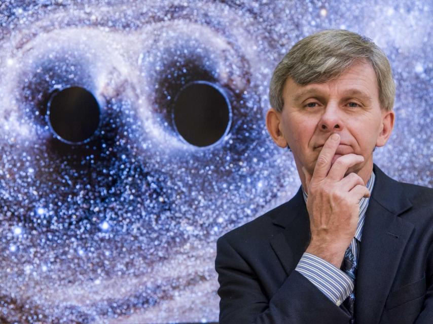 El físico David Reitze junto a dos agujeros negros.