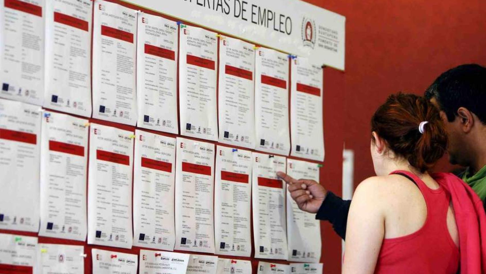 Una pareja consulta un tablón de ofertas de empleo.