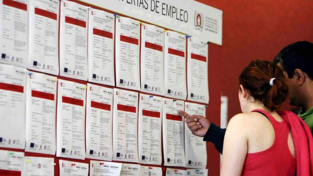 Una pareja consulta un tablón de ofertas de empleo.