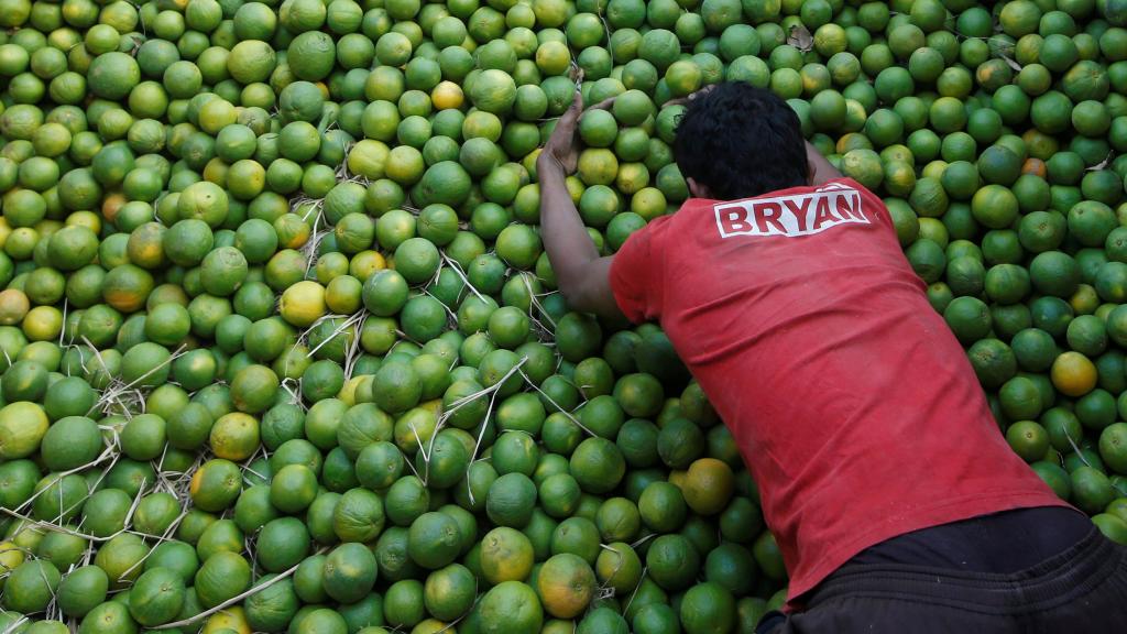 Un trabajador descarga limas en Mumbai.